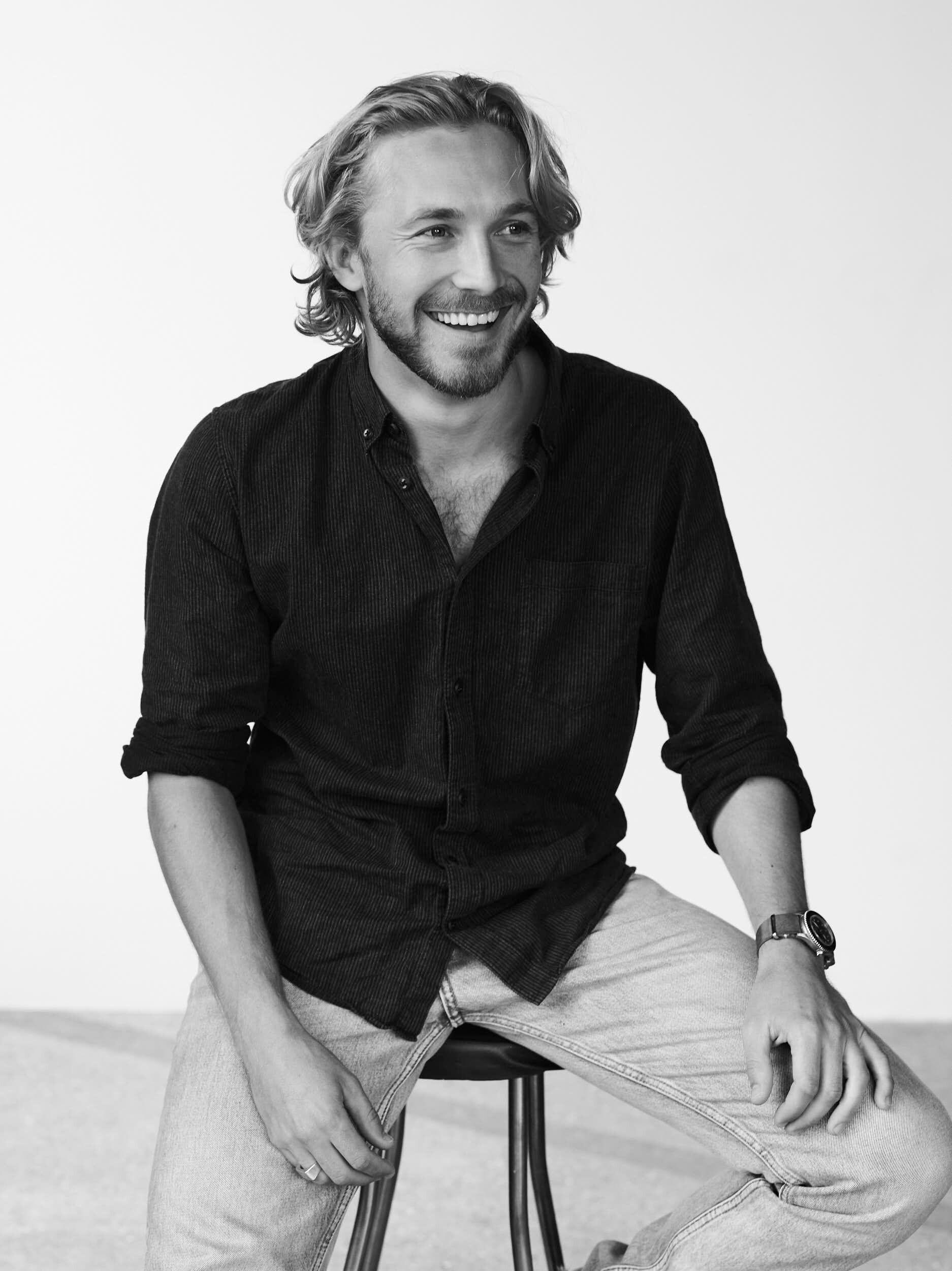 Andreas Jessen smiles while seated on a stool against a light background.