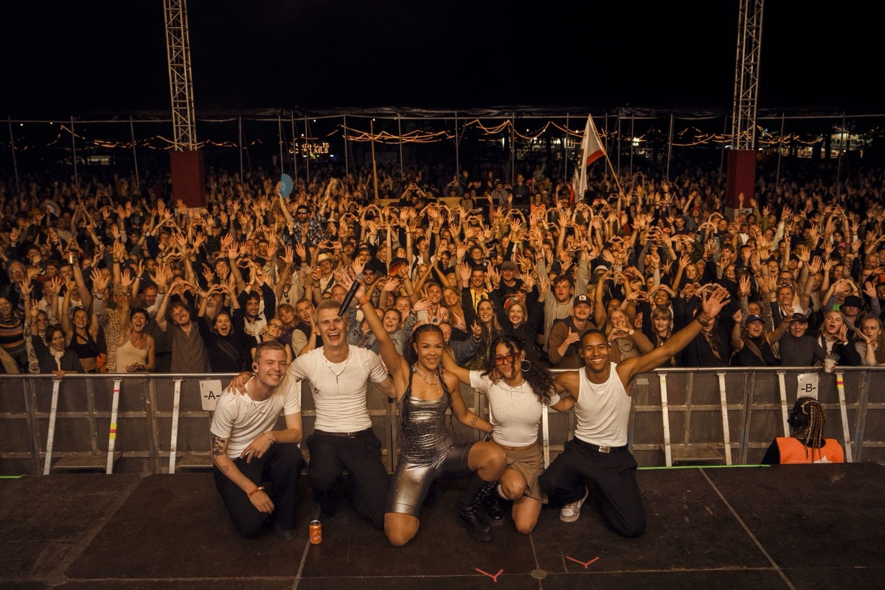 Bathsheba and team celebrate on stage in front of a cheering crowd at a festival.