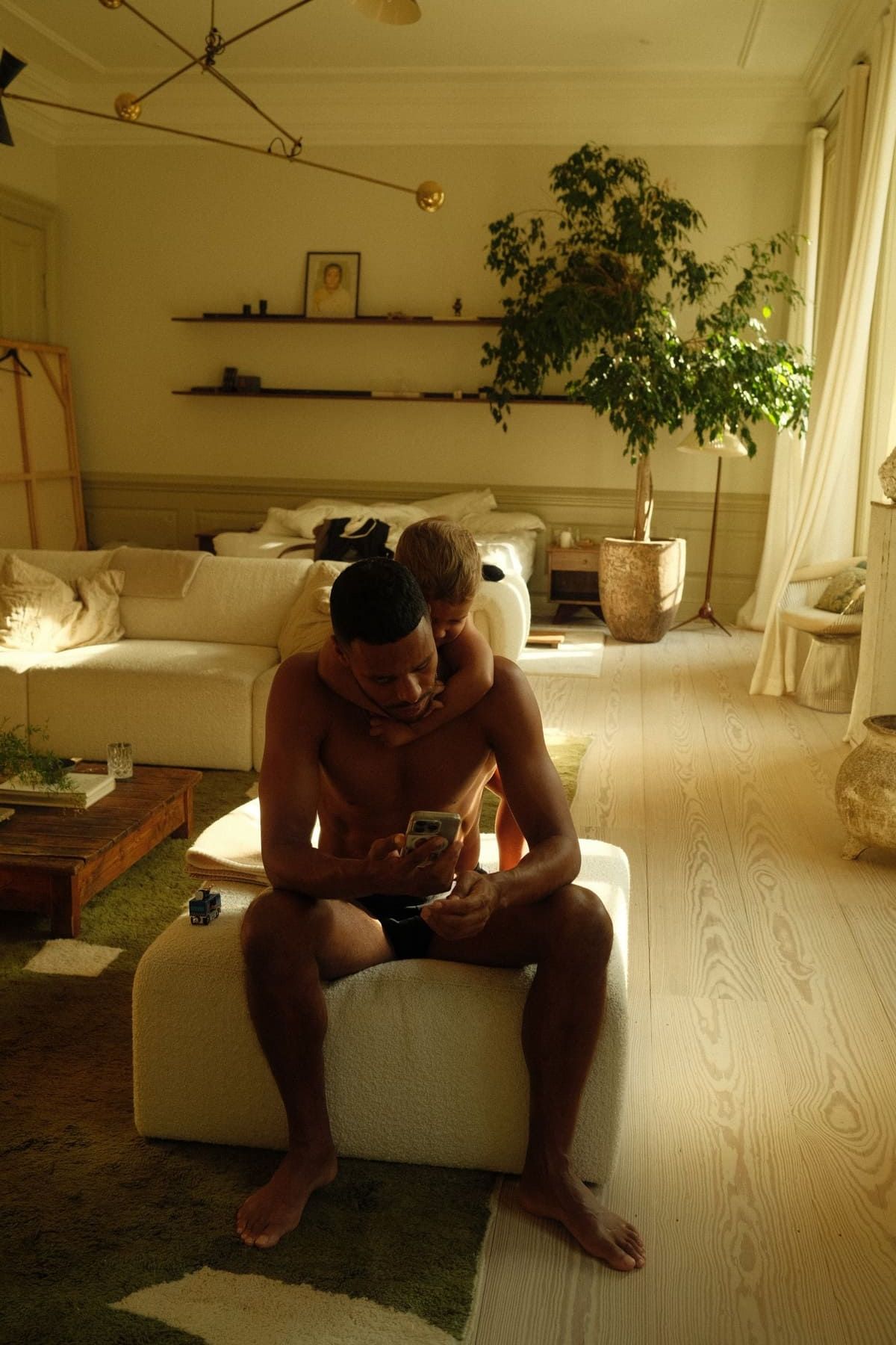 Mathias Zanka sitting on a couch, using a phone in a bright, modern living space.