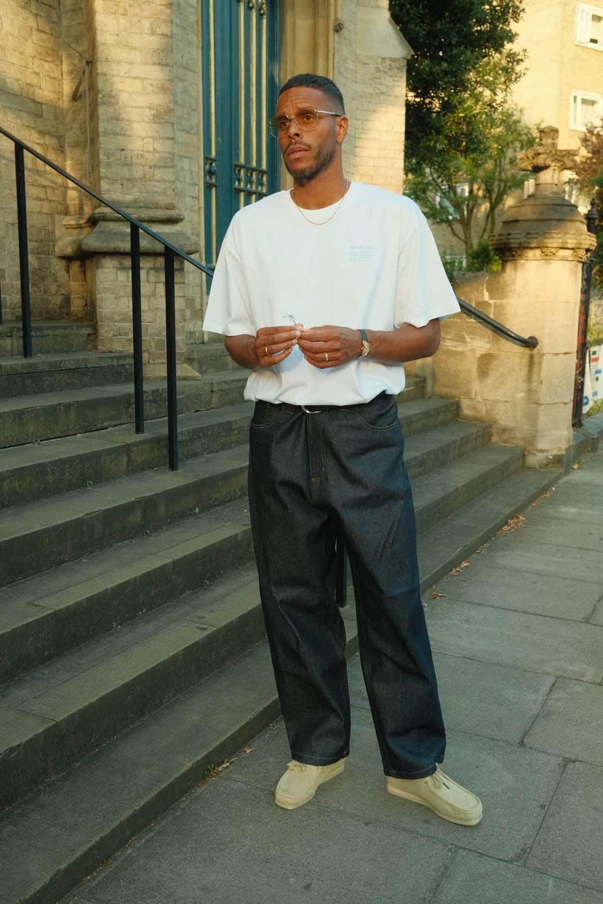 Mathias Zanka stands on stone steps, wearing a white t-shirt and dark jeans.
